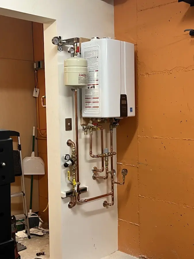 Plumbing technician inspecting water heater connections in Crandall